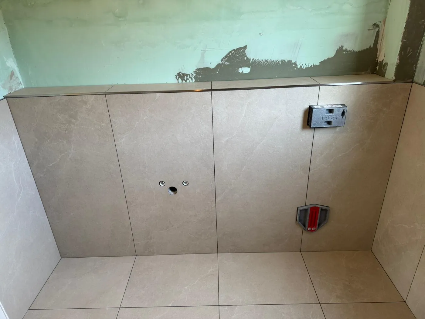 Geflieste Vorwand mit Anschlüssen für Waschtisch und WC