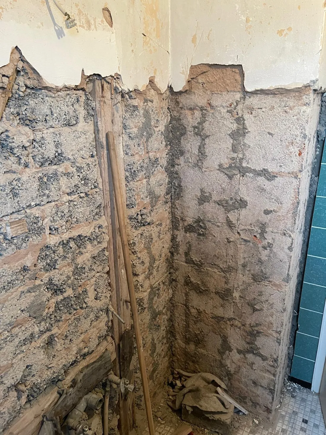 Bad im Rückbau mit freigelegtem Mauerwerk und Holzteilen