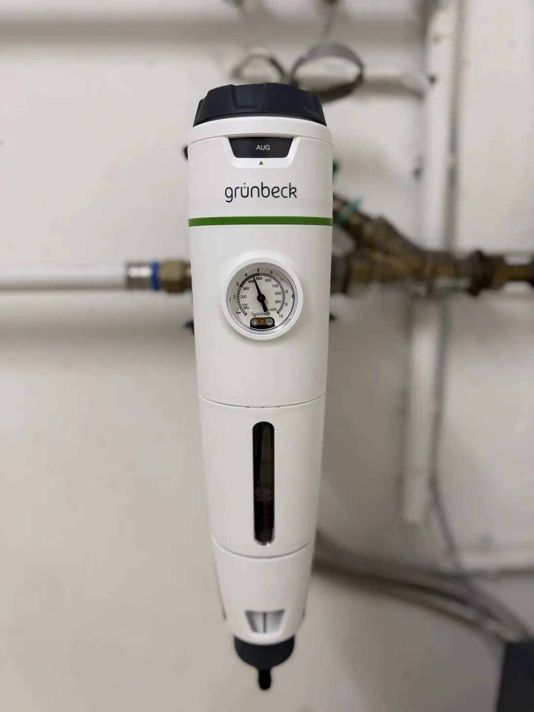 Weißer Grünbeck-Rückspülfilter mit Manometer, Sichtfenster und Monatsanzeige an einer Kellerwand